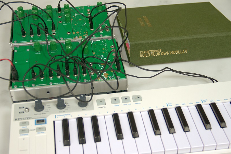 Euroclack synthesizer on a desk with a keyboard and the book